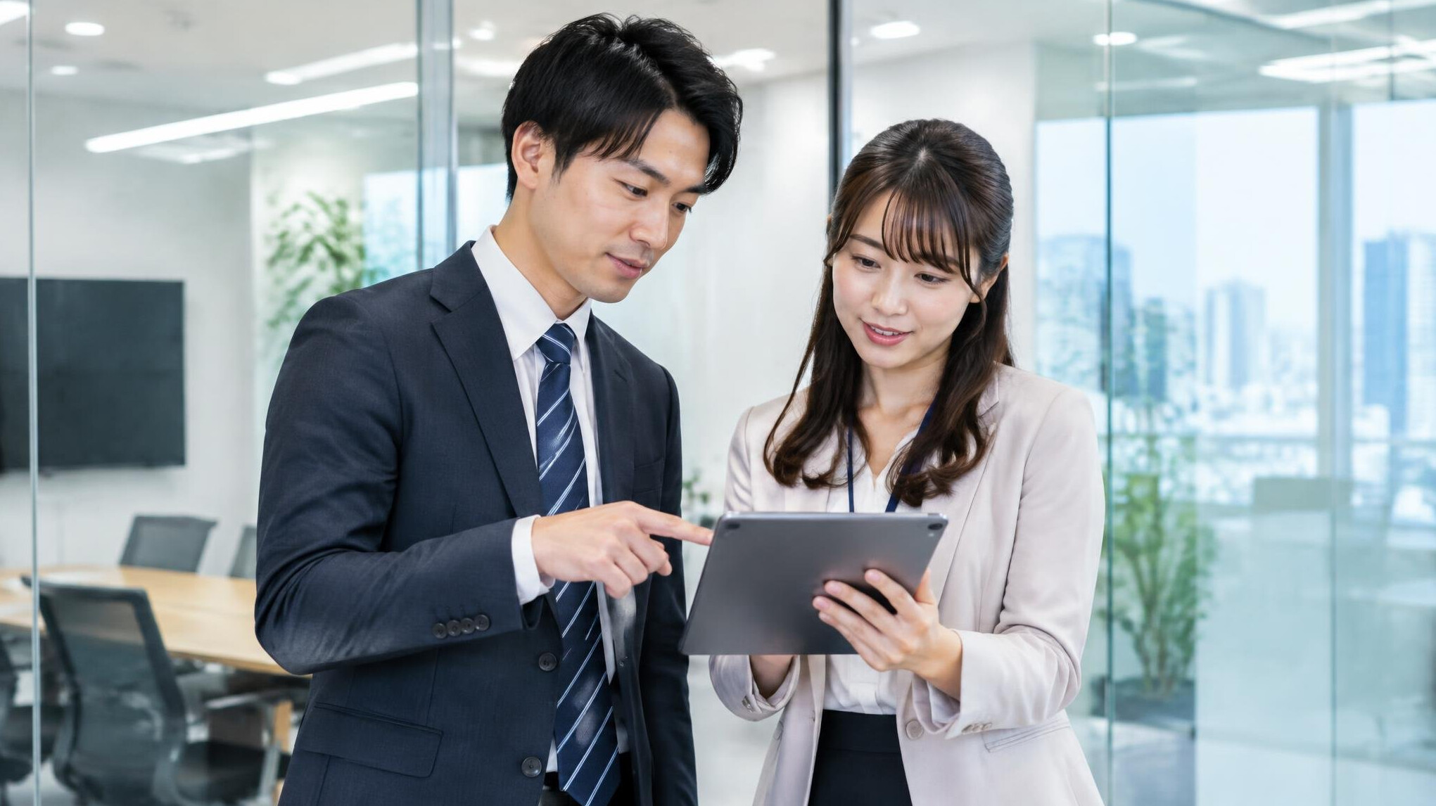 Two colleagues discussing information on a tablet in a meeting room