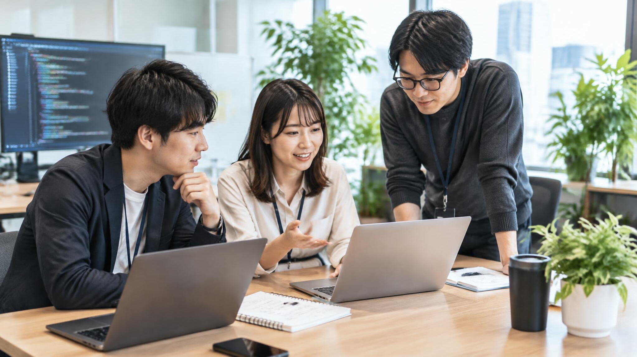 Small team gathered around a desk discussing a project in a modern office